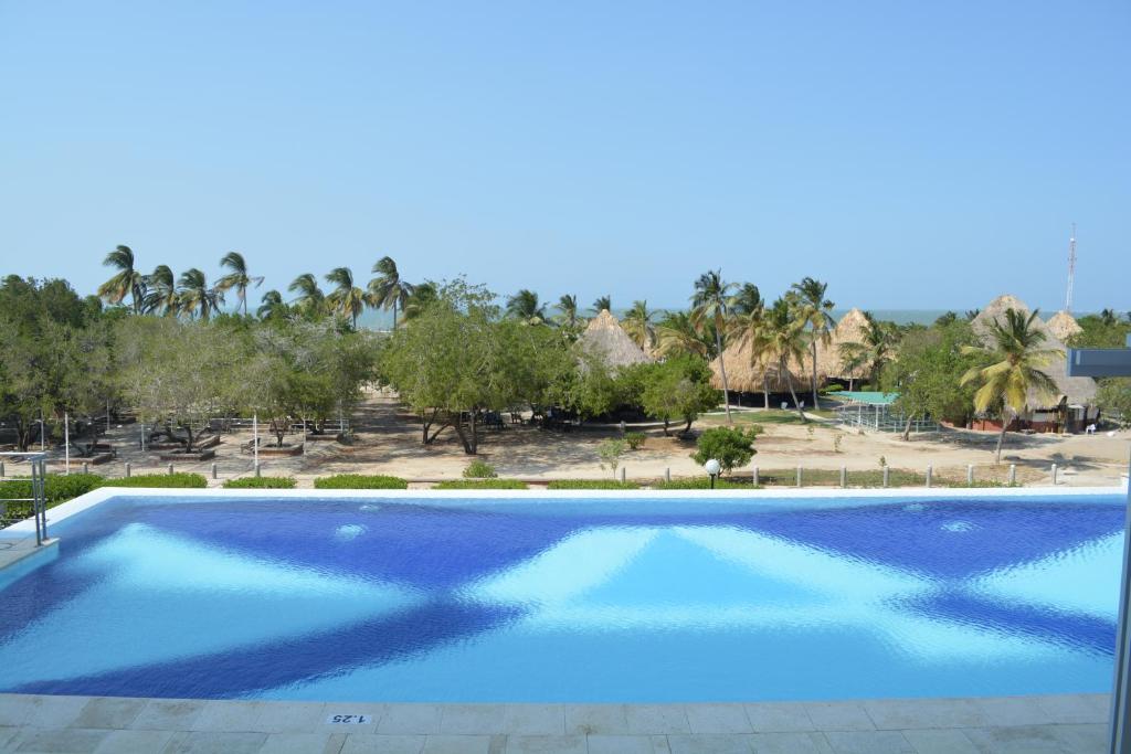 TubaráHotel Isla Verde的一个种有棕榈树的大型蓝色游泳池