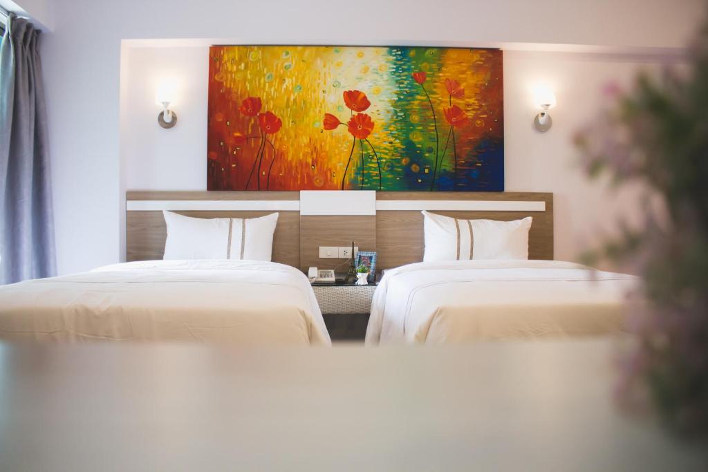 曼谷曼谷新时代酒店的配有绘画的酒店客房内的两张床