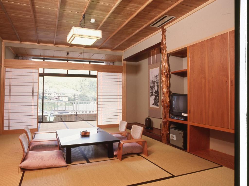 阿智村汤多利里伊那华日式旅馆的客厅配有桌椅和电视。