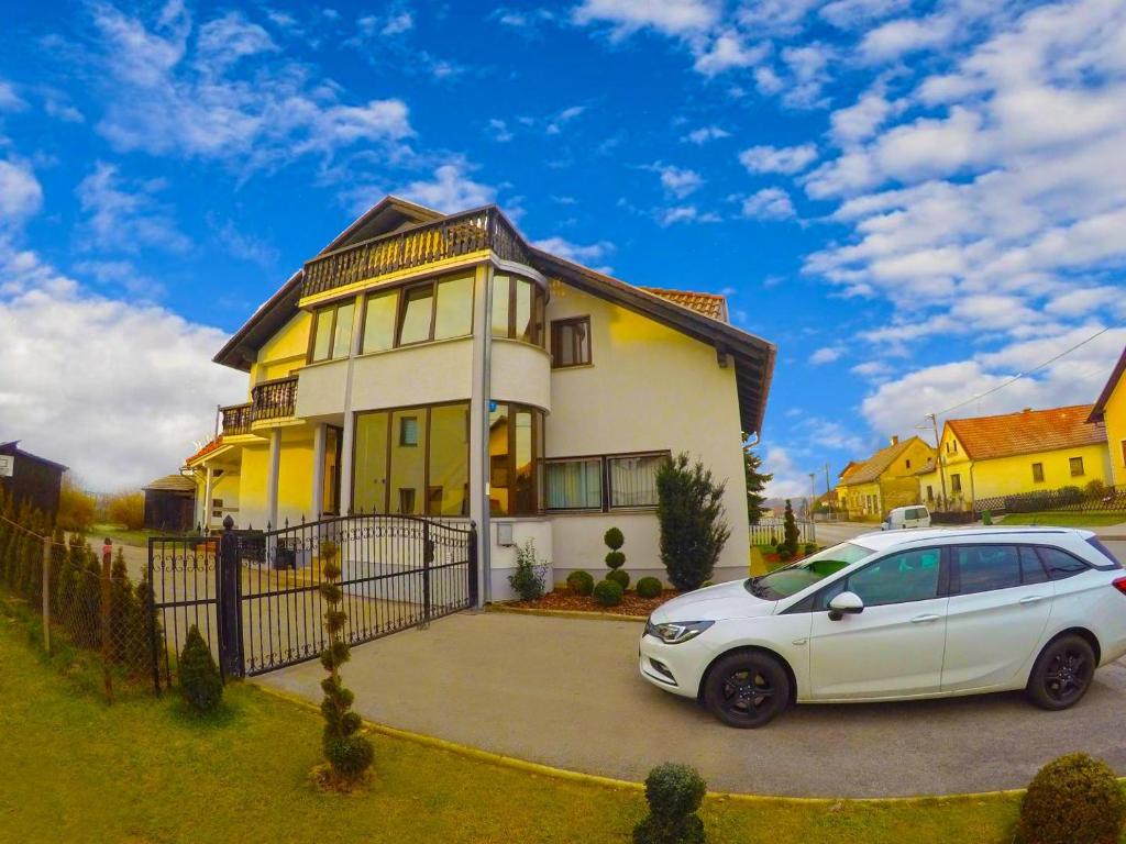 圣马丁娜穆里Apartmani Oletić 4*的停在黄色房子前面的白色汽车