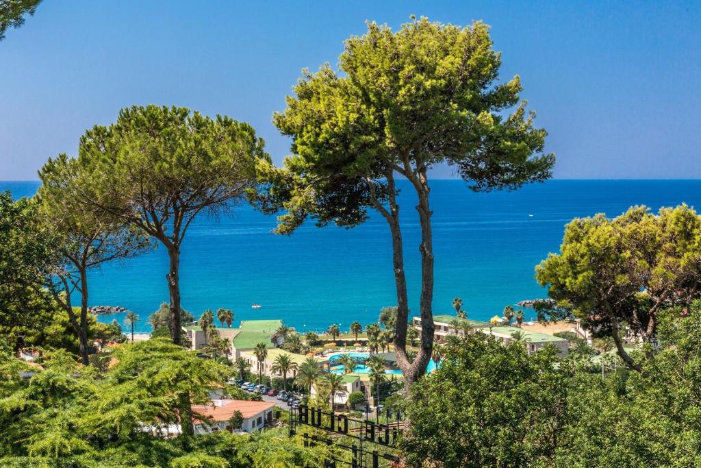 贝尔韦代雷Club Residence La Castellana的享有树木和海洋的度假胜地美景