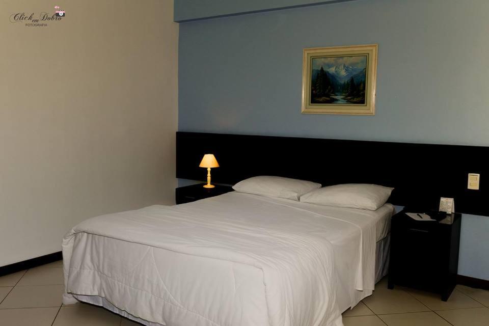 马卡埃水晶酒店的卧室配有一张带灯的白色大床