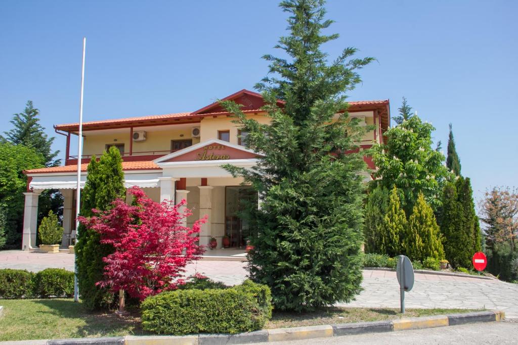 纳乌萨玛西亚斯阿斯特拉斯酒店 的前面有树木和灌木的房子