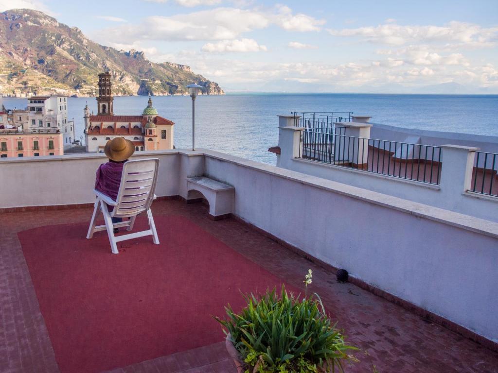 阿特拉尼Casa Almagio - Atrani Amalfi coast - terrace & seaview的坐在阳台上的椅子上,欣赏海洋美景的人