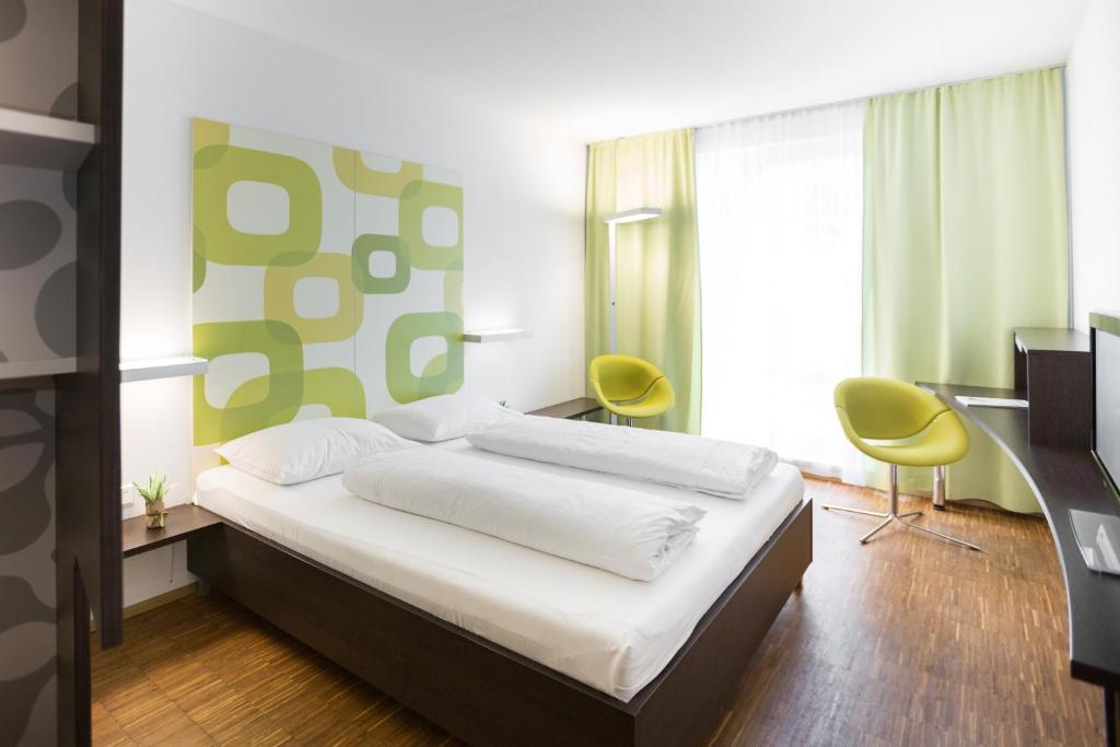 多瑙河畔克雷姆斯克莱姆斯酒店的一间卧室配有一张床和两张黄色椅子