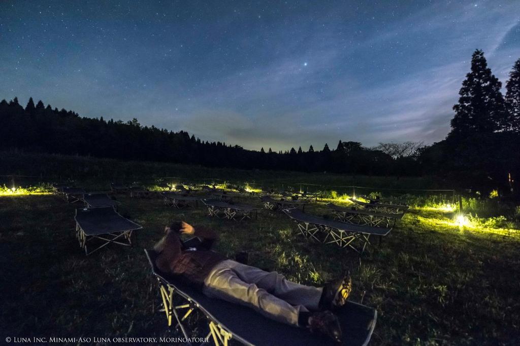 南阿苏村南阿苏月神天文台/森林画室旅馆的夜间躺在田野的长椅上的人