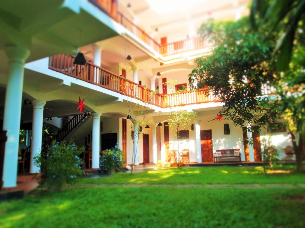 乌纳瓦图纳Unawatuna Nor Lanka Hotel的一座大型白色建筑,设有阳台和庭院