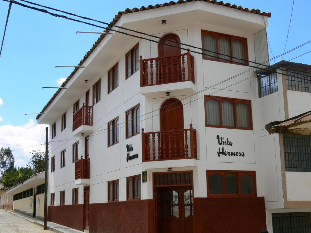 查查波亚斯Hostal Vista Hermosa的白色的建筑,在街上设有红色的阳台