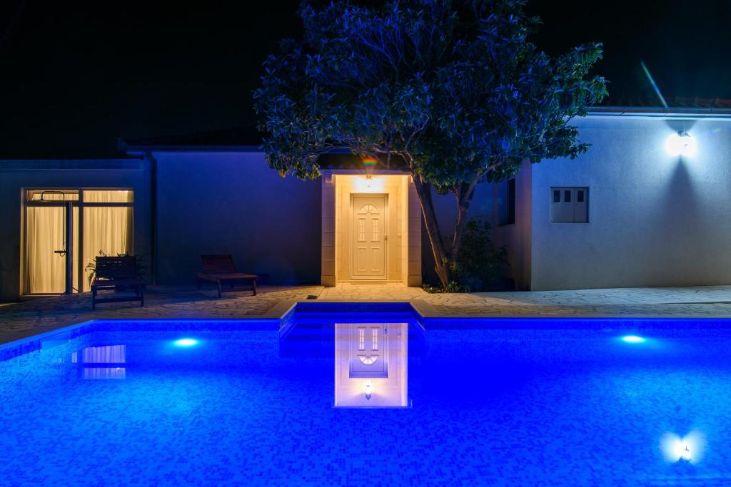 卡什泰拉Villa Lado with private pool near Split的夜间在房子前面的游泳池