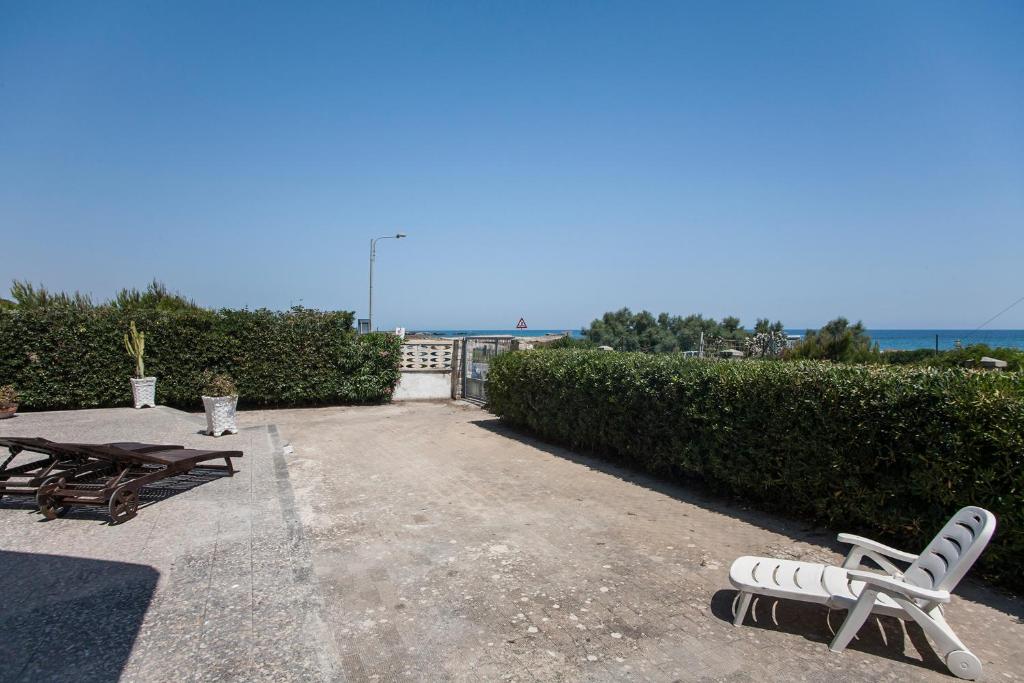 新福卡Villa Mare di Puglia m552的庭院配有两把椅子、一张桌子和长凳