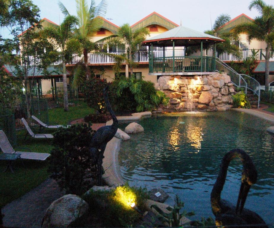 Tinaroo迪纳鲁湖度假酒店的一座有天鹅的房子前的游泳池