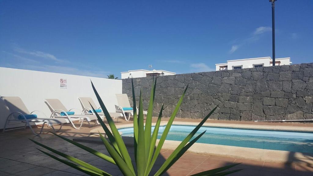 普拉亚布兰卡Casa Avellana的享有带椅子和墙壁的游泳池的景色