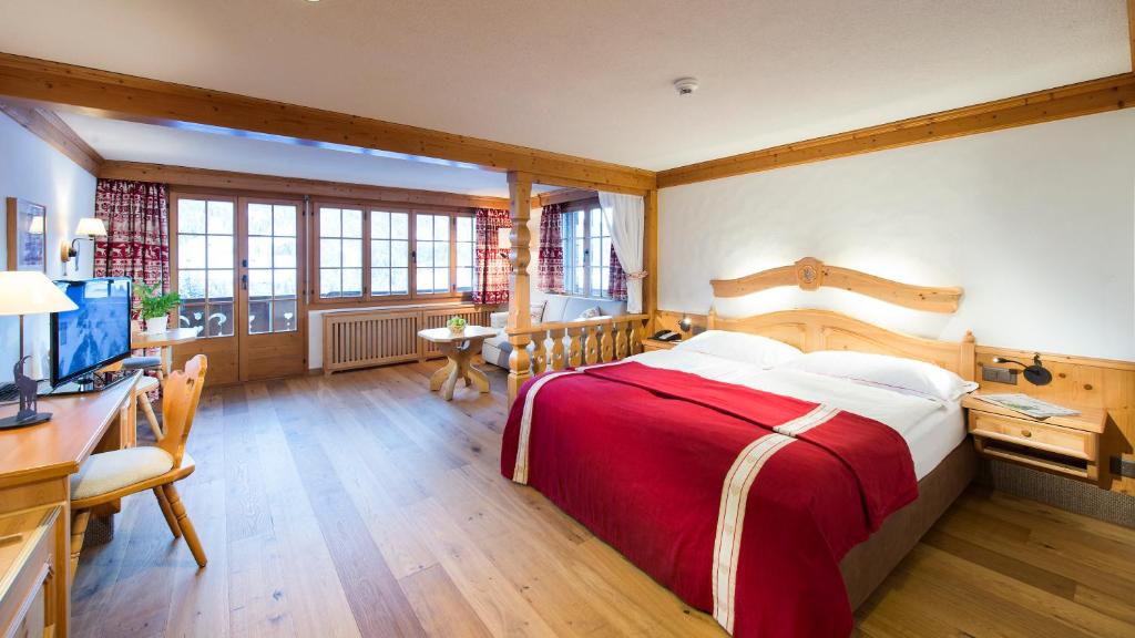 格施塔德Hotel Le Grand Chalet的一间卧室配有一张床、一张书桌和一台电视