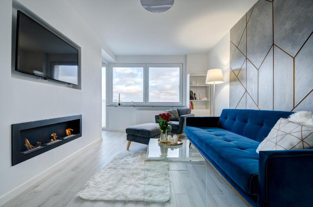 格丁尼亚Modern Place Apartament przy plaży的客厅设有蓝色的沙发和壁炉