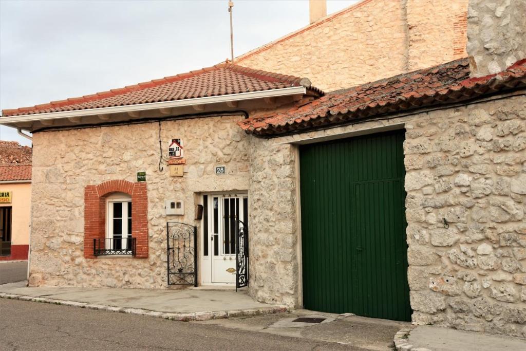 Montemayor de PilillaCasa Rural El Camino的街道上一座石头建筑,设有一扇绿门
