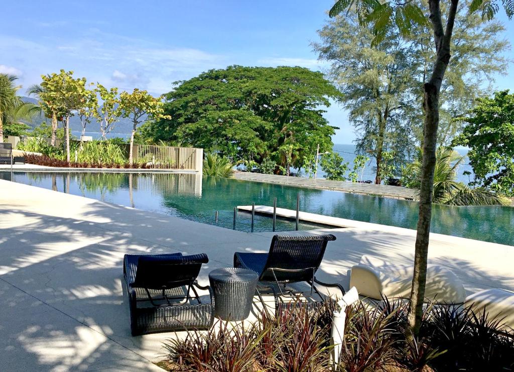 峇都丁宜峇都丁宜滨海套房公寓的游泳池畔的两把椅子和一张桌子