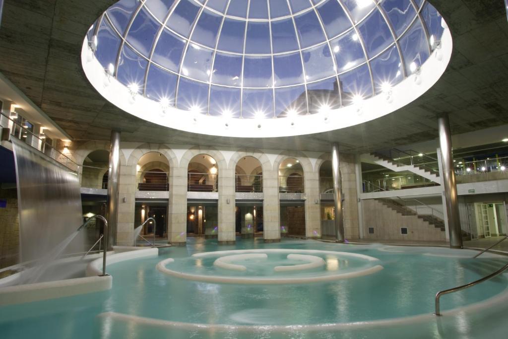 蒙达里斯-瓦尔内亚里奥孟达利兹浴场酒店的一座带玻璃圆顶的建筑中的游泳池