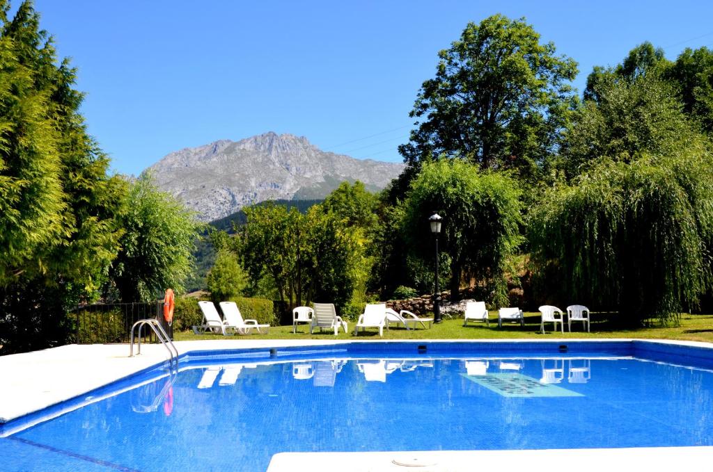 奥耶多Hotel Infantado的一个带椅子的游泳池,后方是一座山。