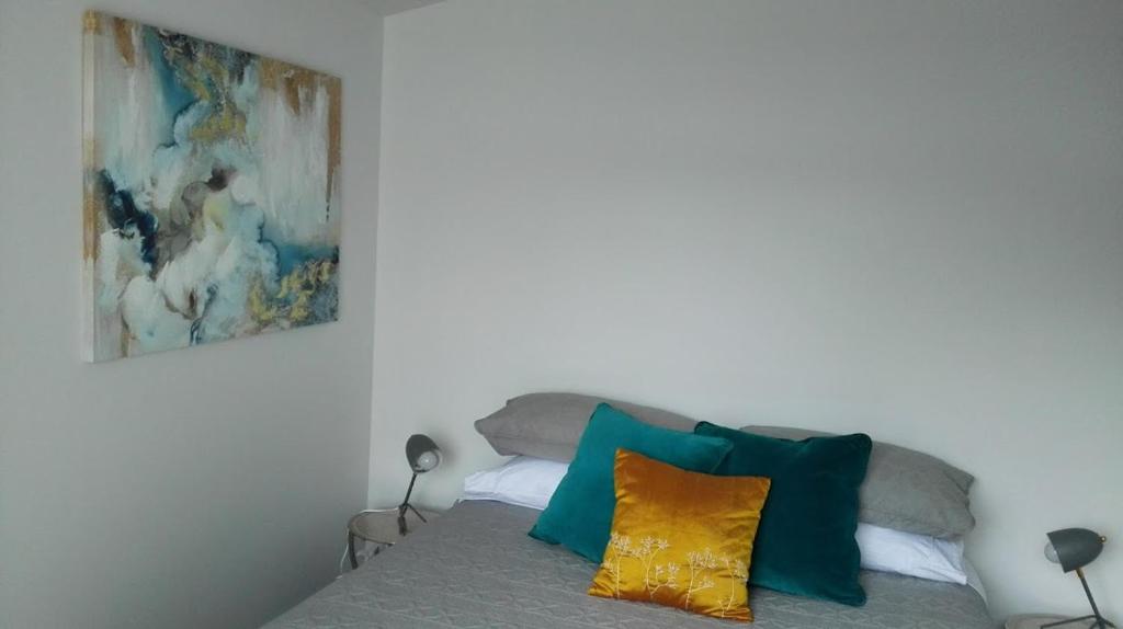 纳尔逊Villa on Milton的一间卧室配有一张带色彩缤纷枕头的床和一幅画