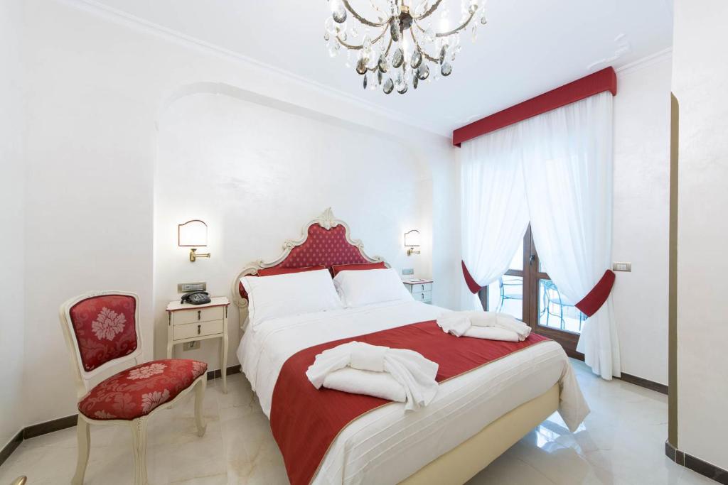马奥莱B&B Palazzo Montesanto的卧室配有红色和白色的床和吊灯。