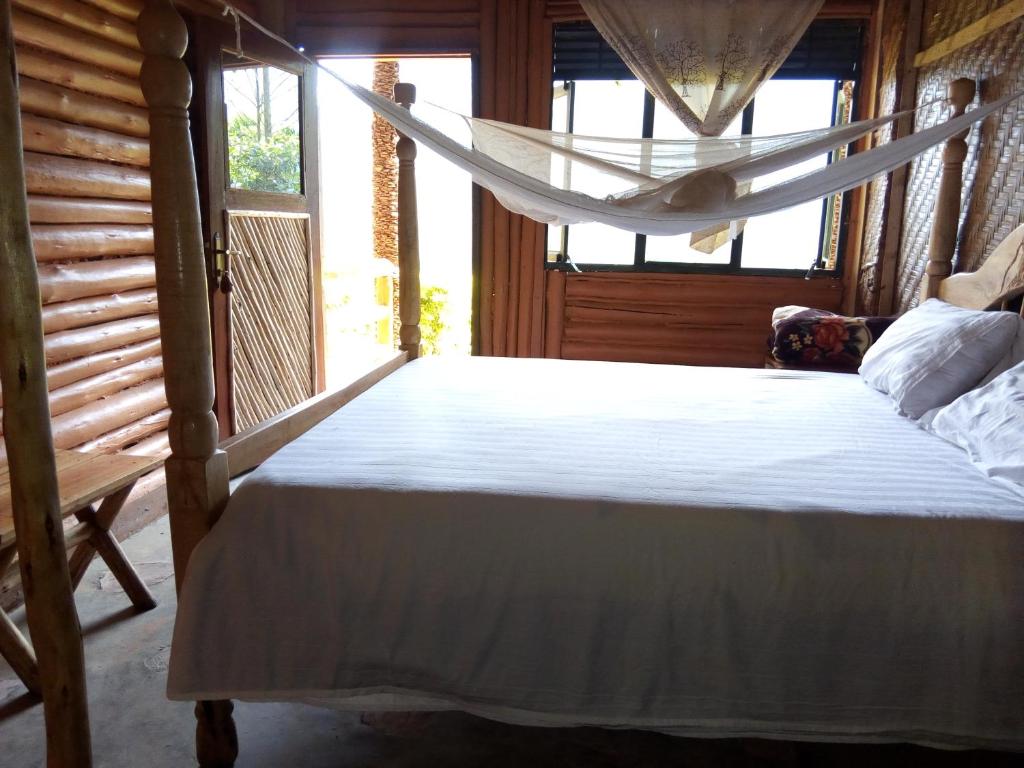 BuhomaBwindi Forest Lodge的带窗户的客房内的一张带吊床的床