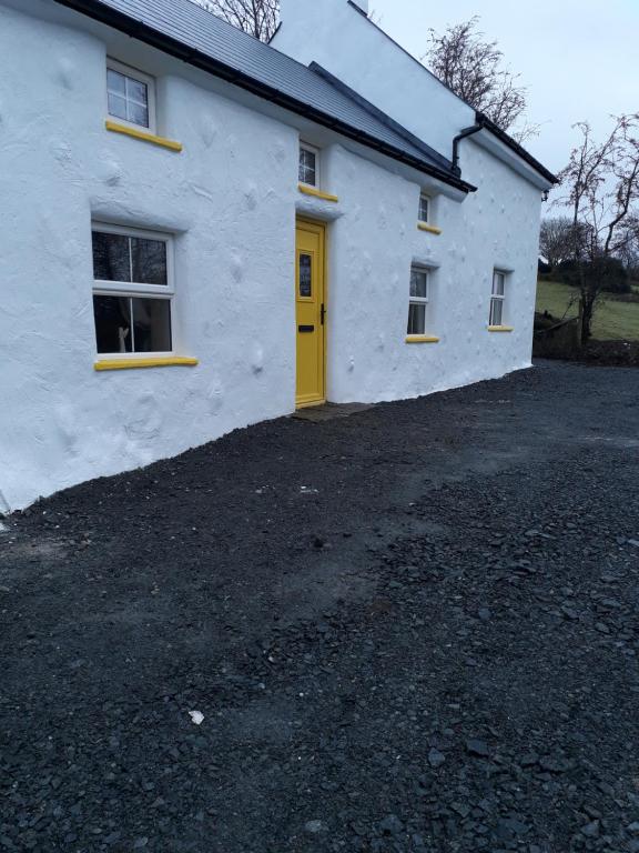 CorderrySams cottage的白色的房子,有黄色的门和车道