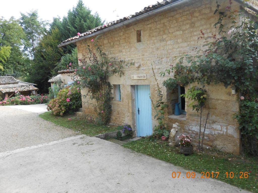 MelleChambre d'hotes Le Fourniou的一座石头房子,有蓝色的门和鲜花