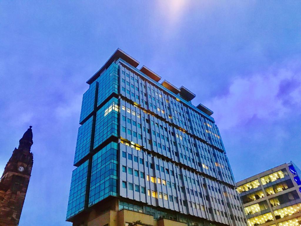 格拉斯哥Glasgow Central Station SKYLINE Apartment with Parking (2 bedrooms, 2 bathrooms, 1 living room-Kitchen)的一座高大的蓝色玻璃建筑,设有钟楼