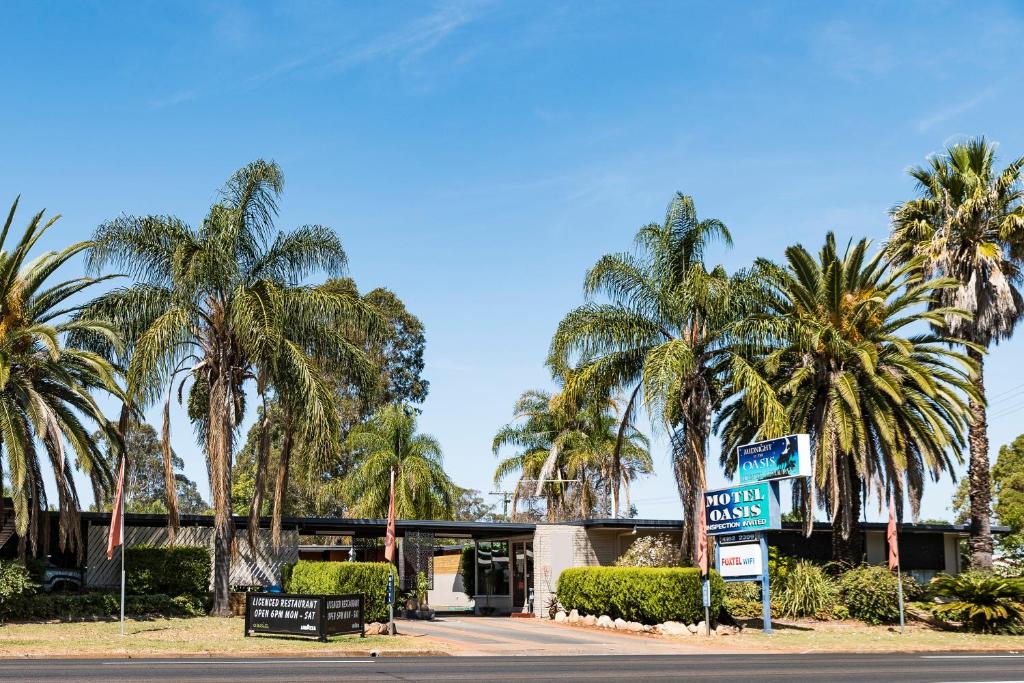 金格罗伊绿洲汽车旅馆的棕榈树建筑前的街道标志