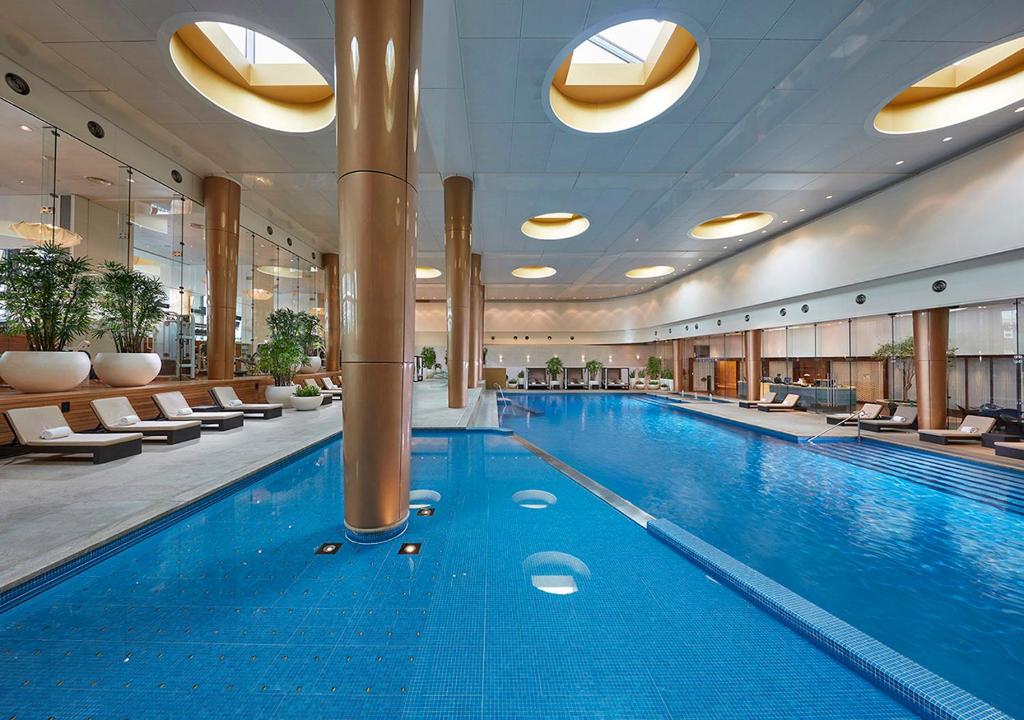 墨尔本Crown Towers Melbourne的酒店的大型游泳池配有椅子
