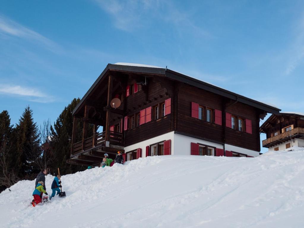 RosswaldChalet Gerbera的一群站在建筑物前的雪中的人