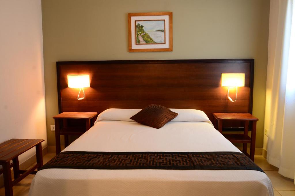 拉巴斯Hotel Portal del Río的一间卧室配有一张带两盏灯的大型白色床。