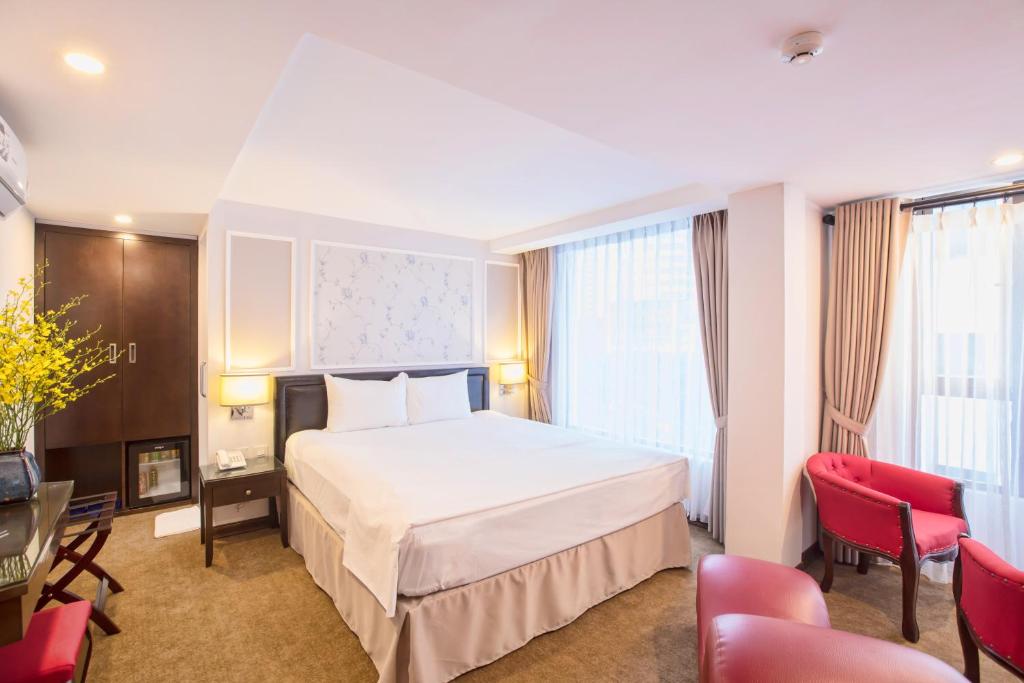 河内河内阿米宫酒店的酒店客房设有一张白色大床和红色椅子。