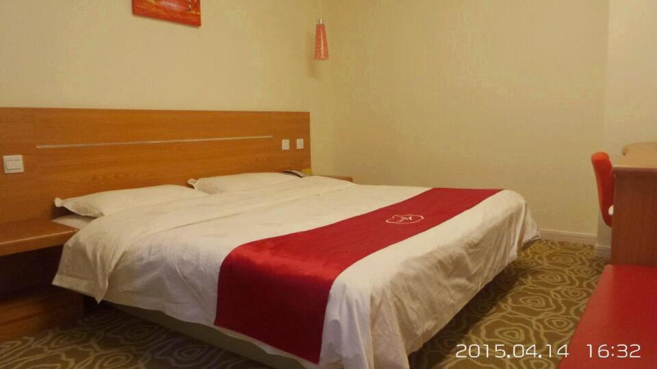 无锡尚客优连锁江苏无锡新区泰伯大道店的一间卧室配有一张带红白毯子的床