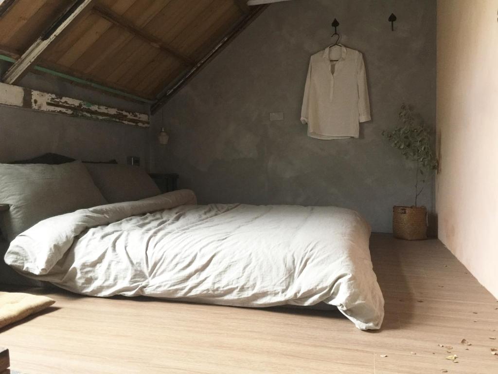 DahanMIAOKO青年旅館的卧室配有白色的床和挂在墙上的衬衫