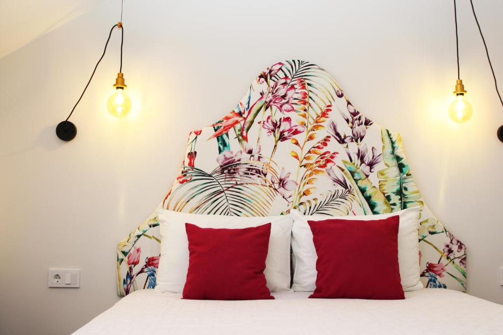 维尔纽斯维尔纽斯公寓酒店的一张带红色枕头的床和花卉床头板