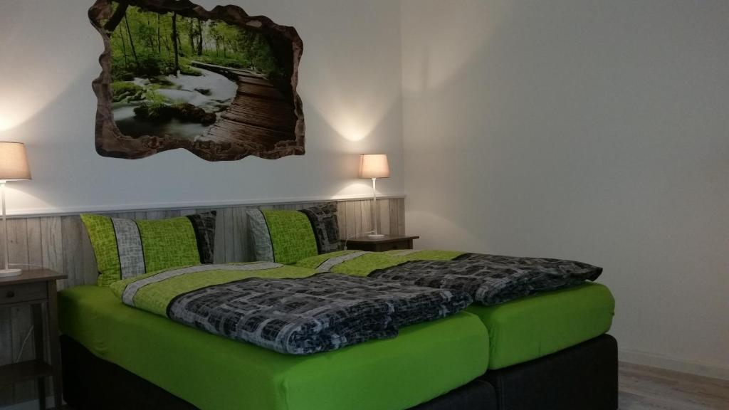 吕贝克Mara的一间卧室配有一张绿色的床、两张桌子和两盏灯。