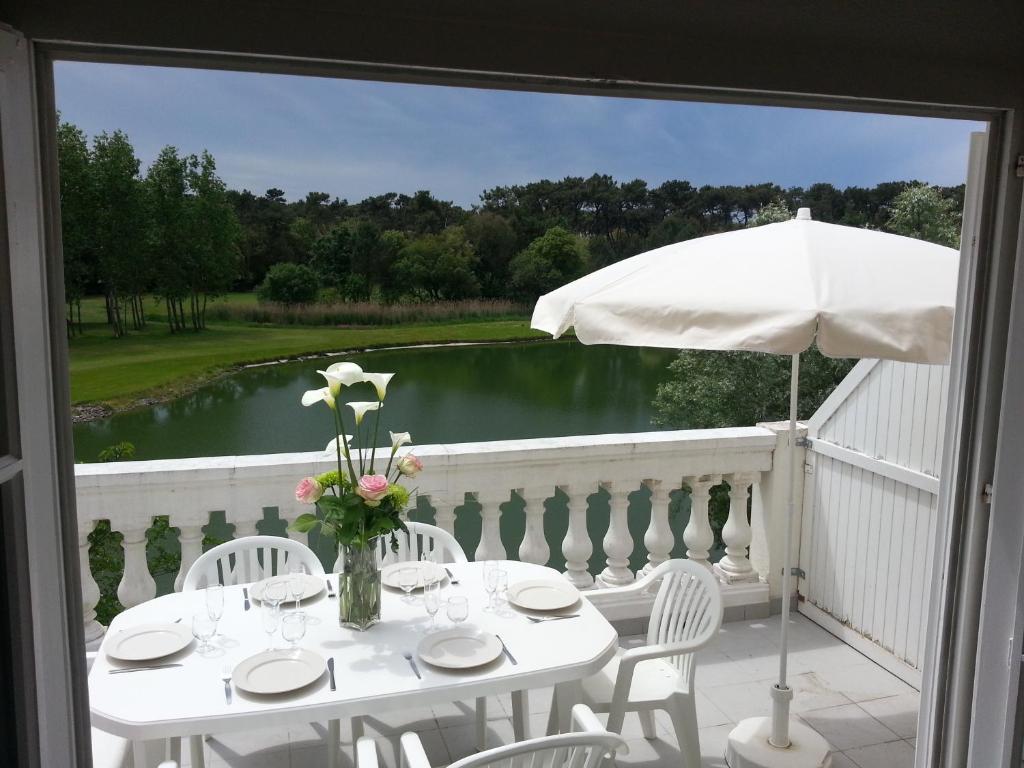 塔勒蒙Port Bourgenay Ile au Pré vue lac et golf的阳台上配有带椅子和遮阳伞的白色桌子