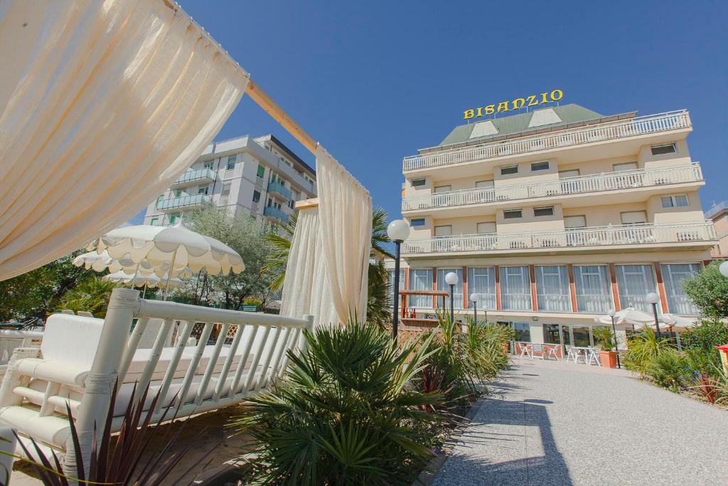 切塞纳蒂科Hotel Bisanzio的一座配有椅子和遮阳伞的酒店,一座建筑