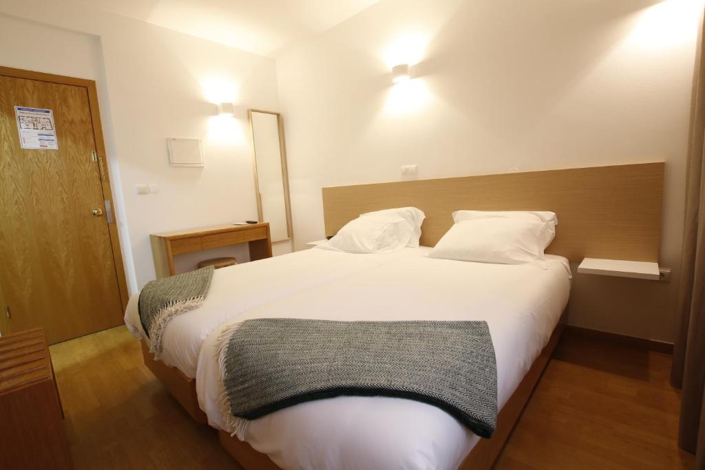布拉干萨Baixa Hotel的卧室配有一张带两个枕头的大白色床