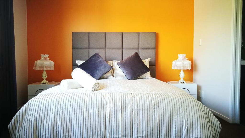 罗托鲁瓦罗托鲁瓦之心公寓的一间卧室配有一张带橙色墙壁的大床