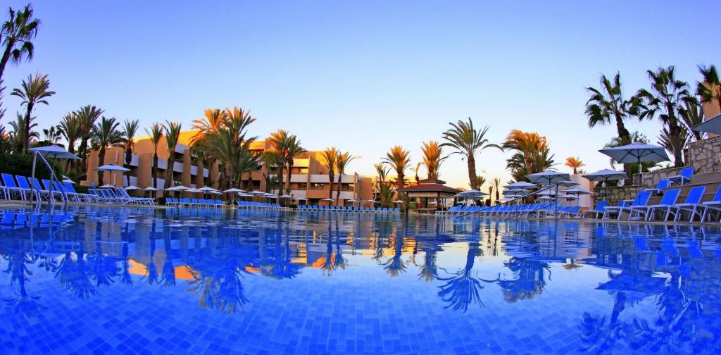 阿加迪尔Dunes d'Or Ocean Club的一个带蓝色椅子和棕榈树的大型游泳池