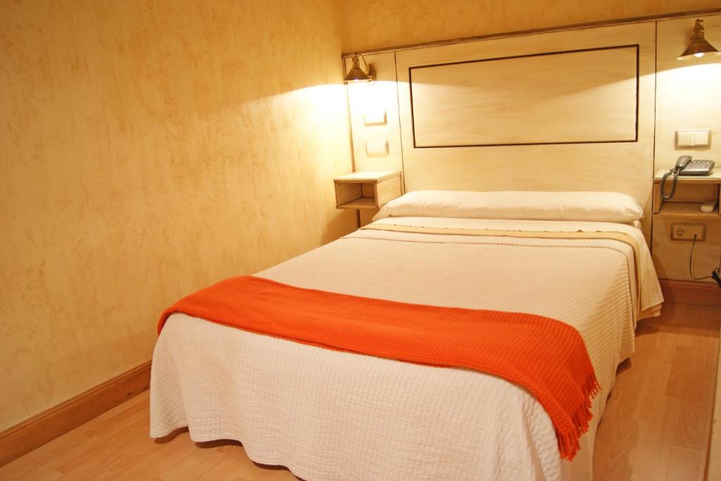 潘普洛纳卡斯蒂略哈维尔酒店的一间卧室配有一张带橙色和白色毯子的床