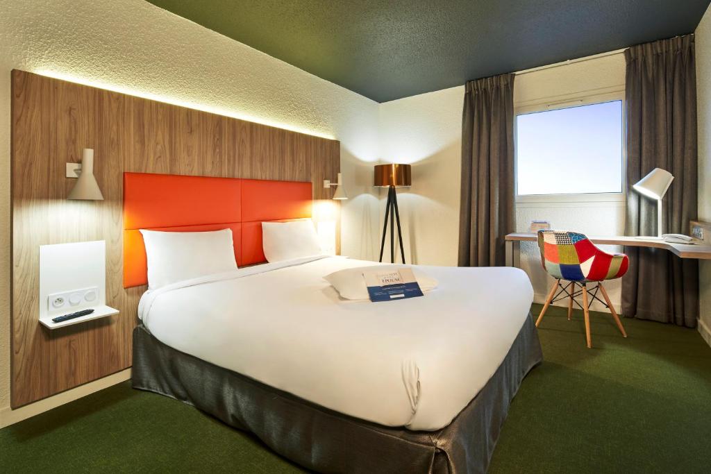 里永里永基克莱蒙费朗北里亚德酒店的酒店客房设有一张大床和一张书桌。