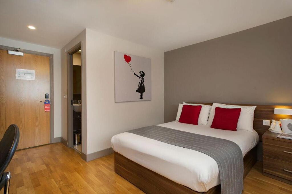 布莱顿霍夫不列颠思达戴酒店的一间卧室配有一张带红色枕头的大床