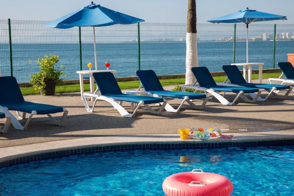 巴亚尔塔港艾佩斯卡多酒店的毗邻大海的带椅子和遮阳伞的游泳池