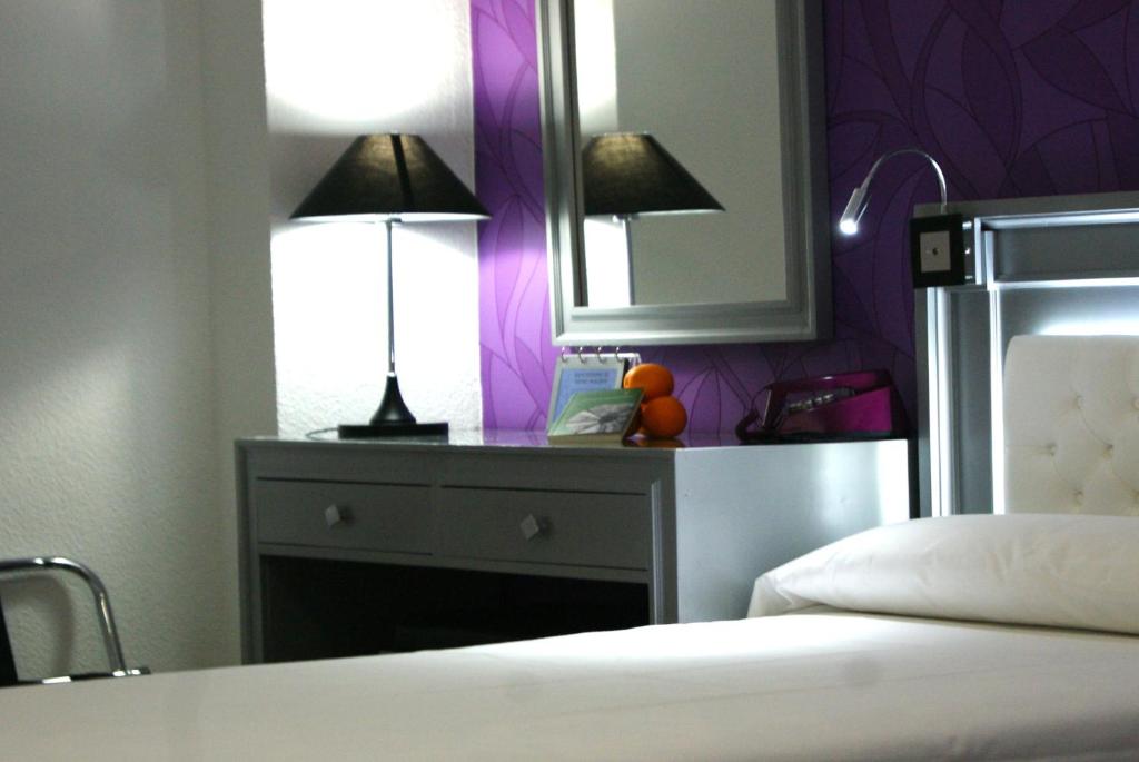 格拉纳达莫利诺斯酒店的一间卧室配有一张桌子、两盏灯和一面镜子