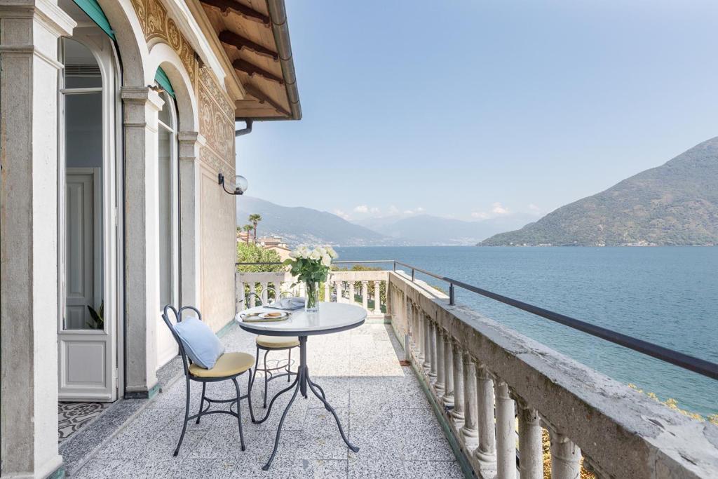 坎诺比奥Villa Maria Hotel的阳台配有桌椅,俯瞰着水域