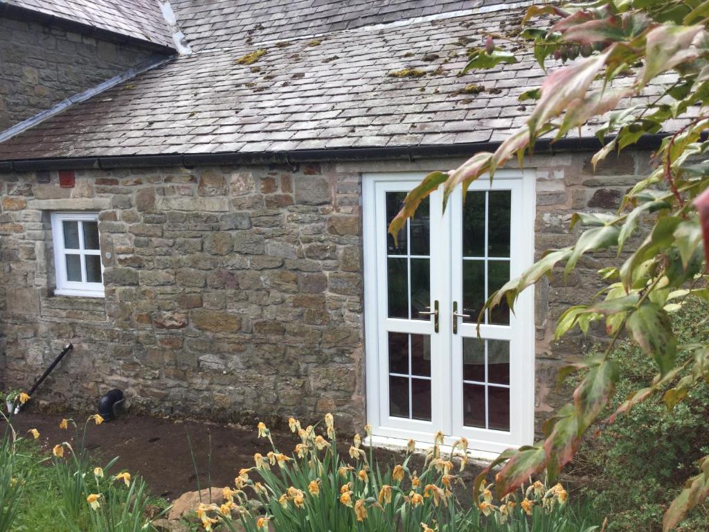 霍特惠斯尔The Snug @ Corry Cottage的白色窗户的石头房子