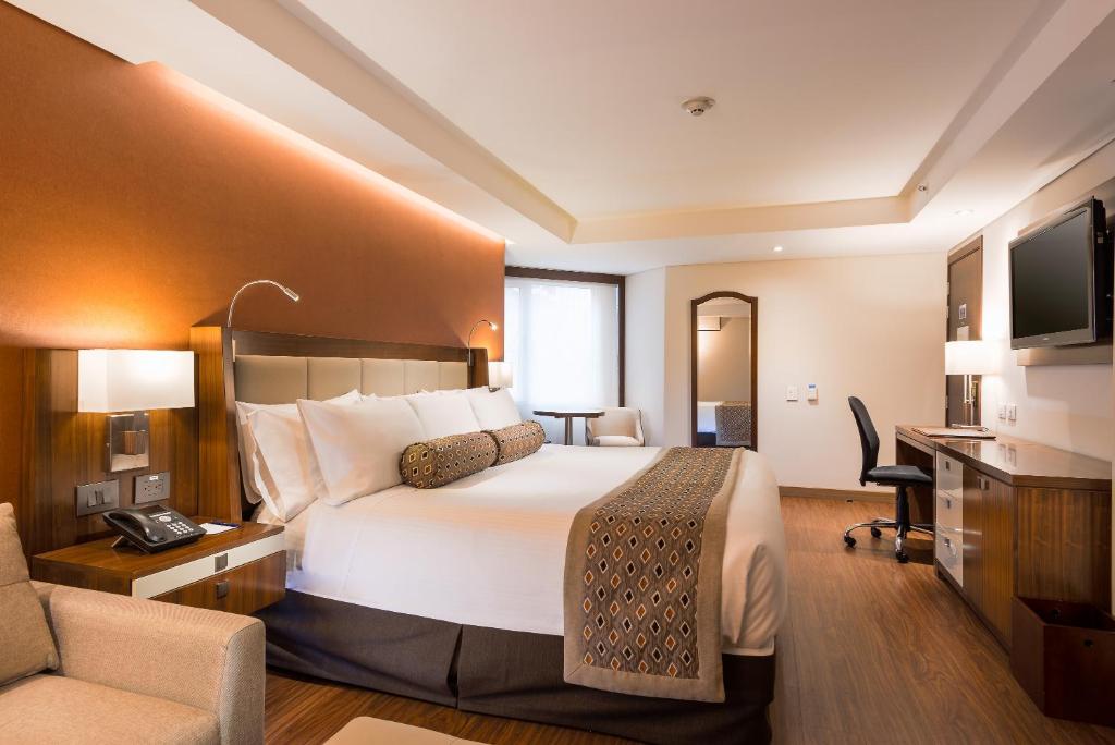 波哥大Hotel Dann Carlton Bogota的酒店客房设有一张大床和一张书桌。